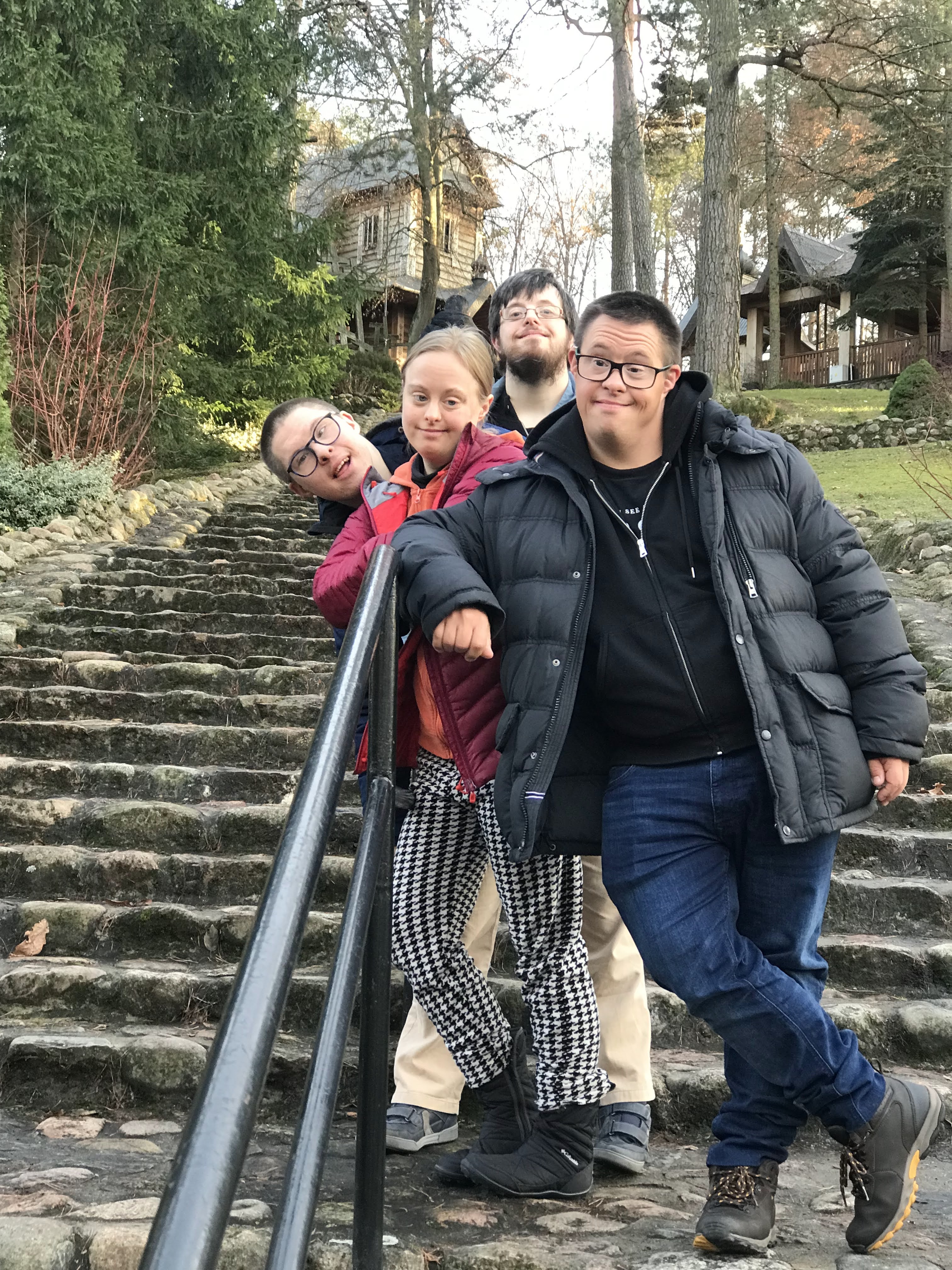 Grupa młodzieży na wycieczce. W tle zabytkowy kościół drewniany.j